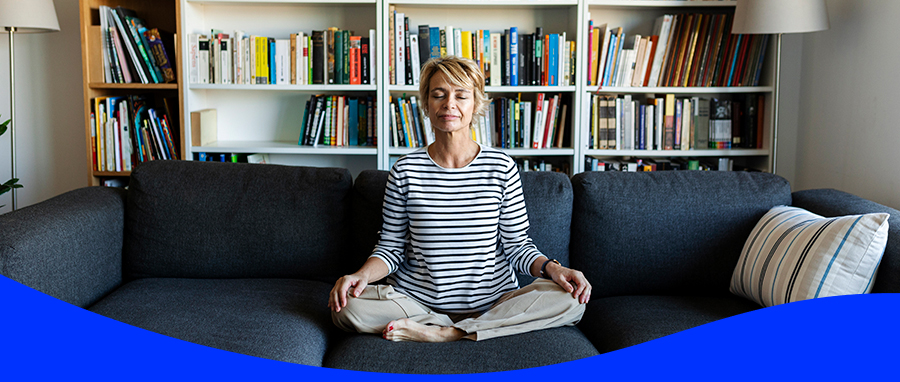 A woman meditating on her sofa